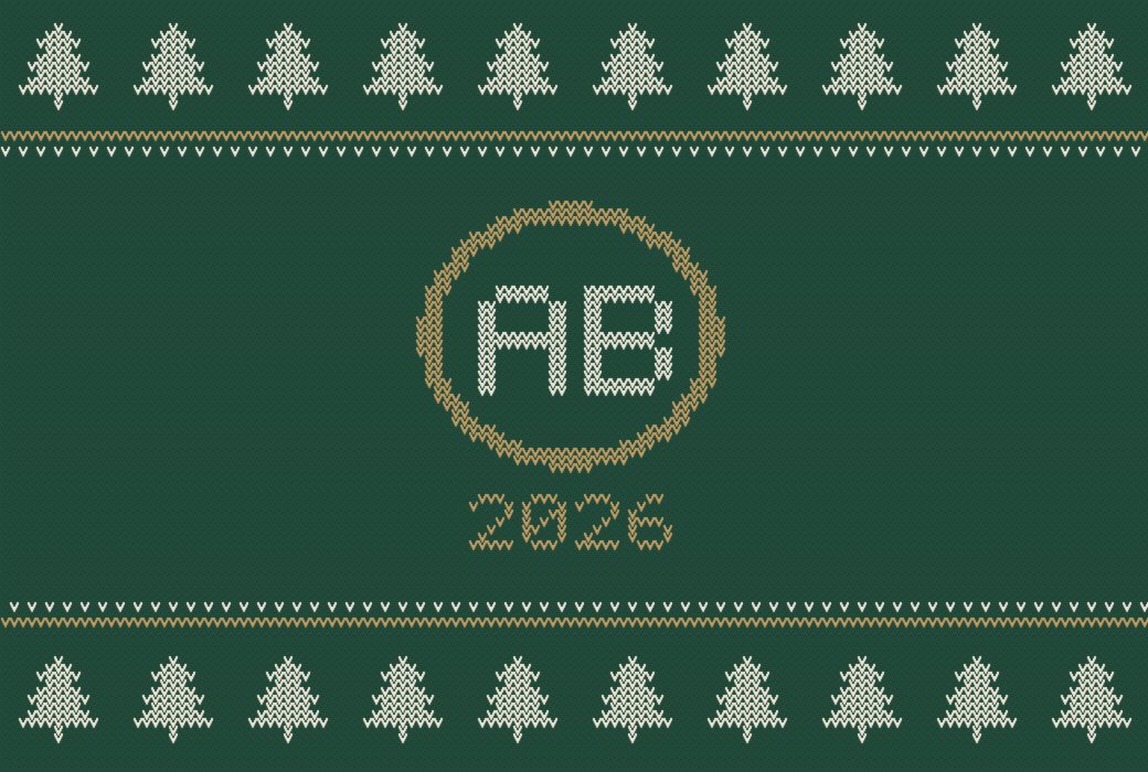 Simulazione a maglia: le iniziali AB dentro un anello dorato e la scritta 2026, su fondo verde fra due file di abeti